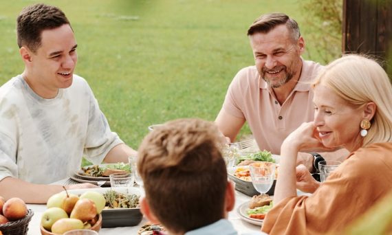 A cheerful family enjoying a meal together outdoors, sharing laughter and warmth.